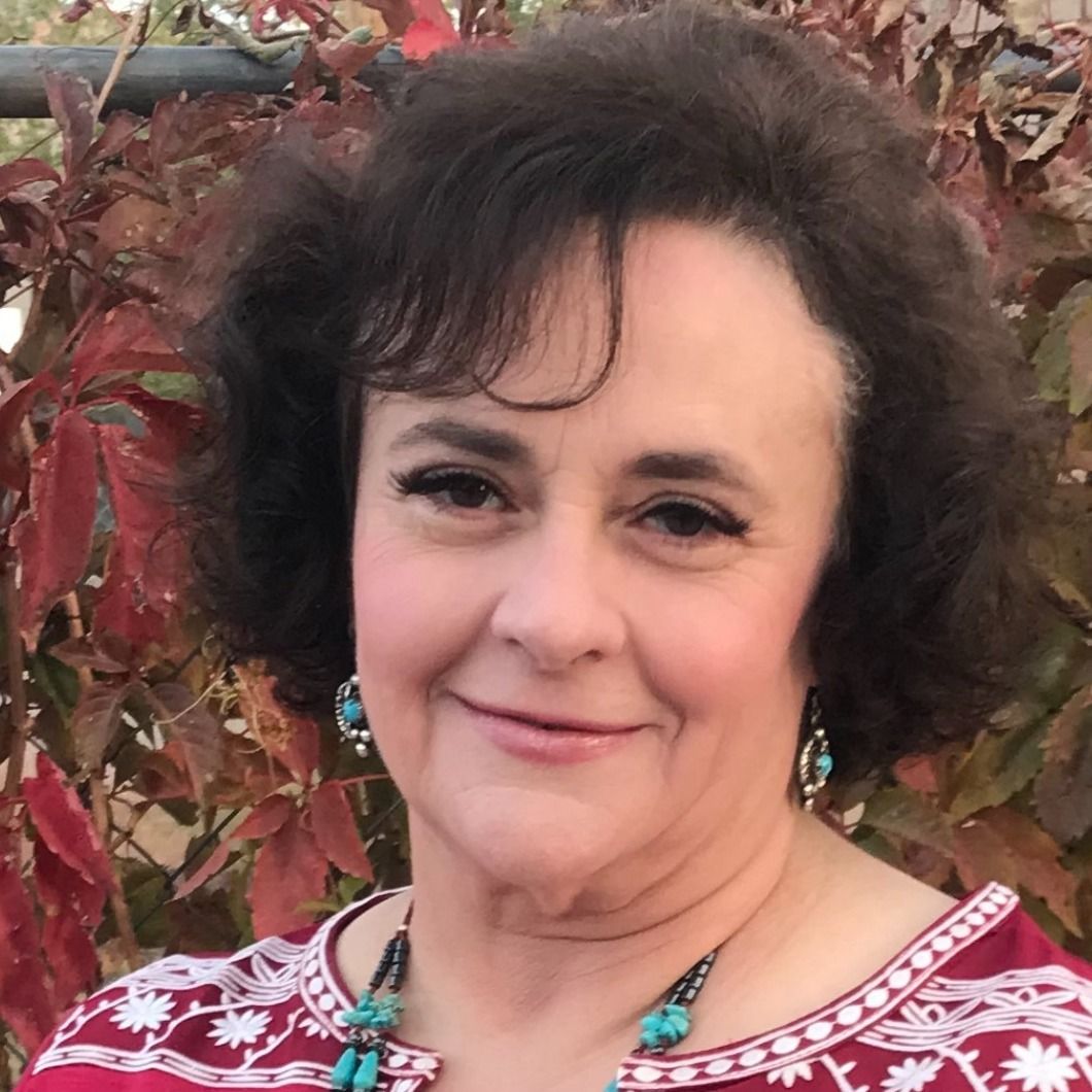 Joanne Yarrish, a certified nurse-midwife, smiling outdoors in front of red autumn leaves.